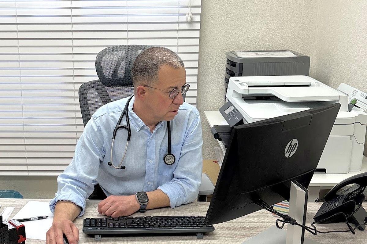 Dr Alex Economakis at his desk in the consulting room